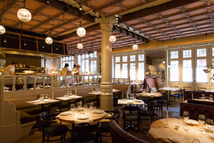 While maintaining an floor plan, the restaurant includes several sections whose unique feel comes from nuanced changes in decor. The main room (below) feels more like a supper club, refined yet still relaxed, whereas the area between the bar and the street windows (above) feel more like a country kitchen, with its rustic light wood chairs, potted plants and checkerboard flooring, as well as the natural lighting flooding in from the street. It is these subtle exchanges that make the Chiltern Firehouse so rich in experience – in that there are so many different experiences to be had in the same space. The original columns and windy layout of the original floorplan also help to create a sense of spatial partitioning. 