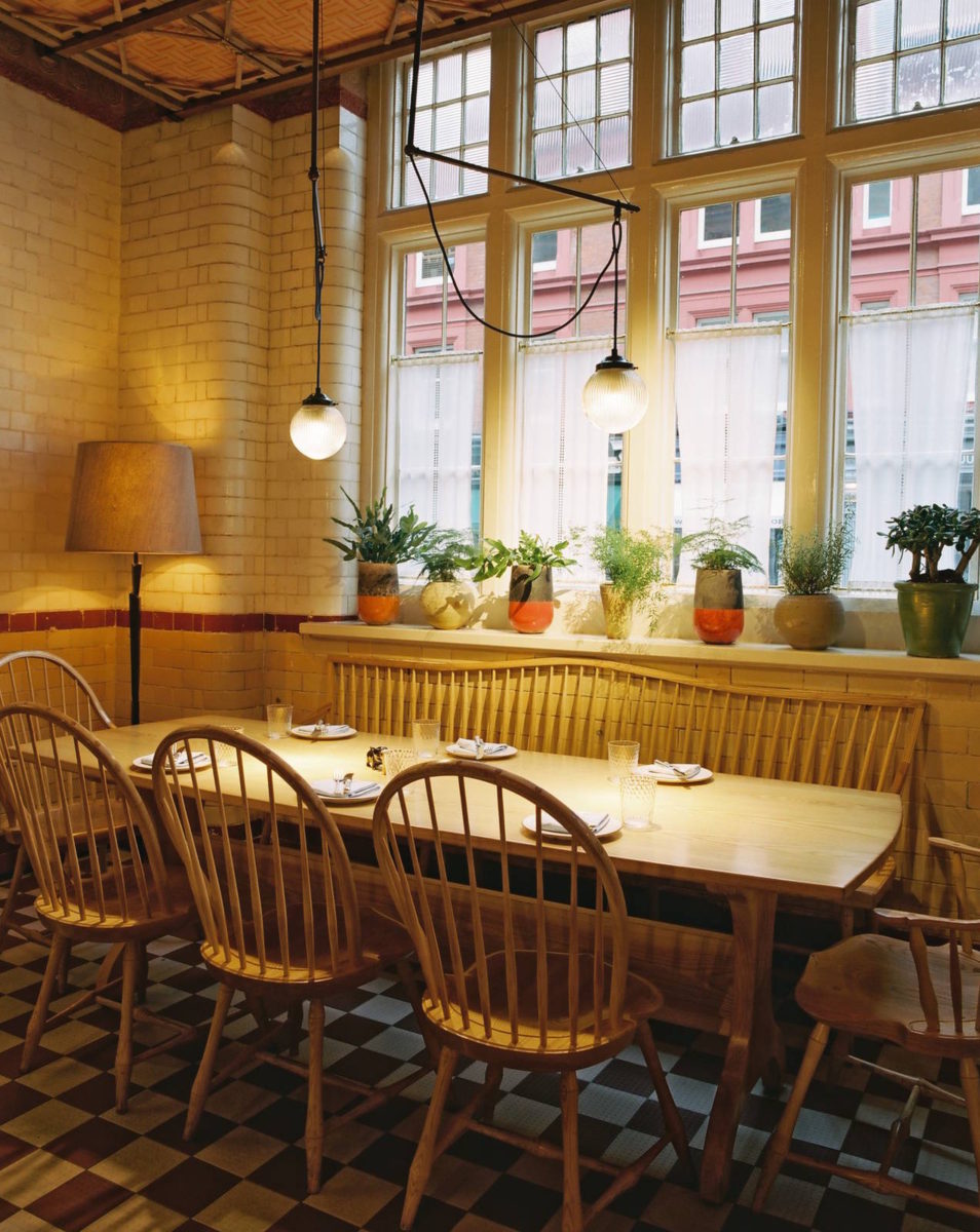 While maintaining an floor plan, the restaurant includes several sections whose unique feel comes from nuanced changes in decor. The main room (below) feels more like a supper club, refined yet still relaxed, whereas the area between the bar and the street windows (above) feel more like a country kitchen, with its rustic light wood chairs, potted plants and checkerboard flooring, as well as the natural lighting flooding in from the street. It is these subtle exchanges that make the Chiltern Firehouse so rich in experience – in that there are so many different experiences to be had in the same space. The original columns and windy layout of the original floorplan also help to create a sense of spatial partitioning. 