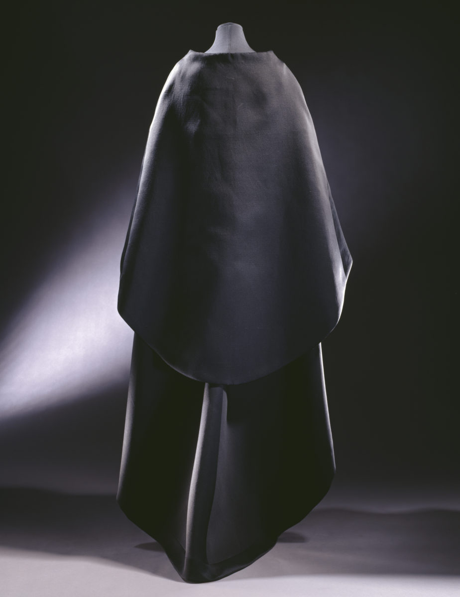 T.39-1974; T.39A-1974 Evening gown and cape Gazar, sleeveless dress with scoop neck . Short in the front and dipping to a slight train at the back - this line is echoed by the cape which front fastens with two large self covered buttons Balenciaga, Paris, 1967