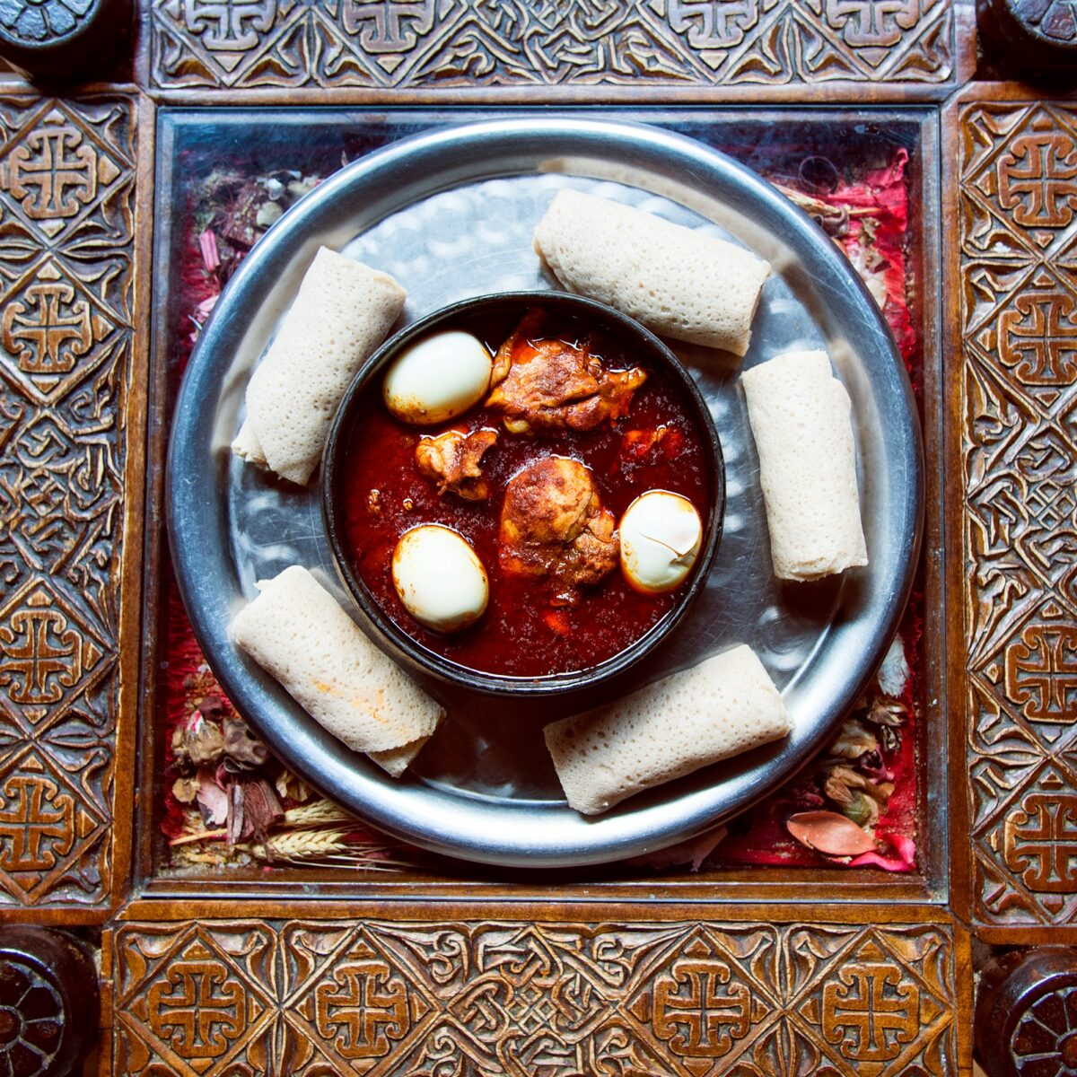 Warsà's deep-red zighinì, with chicken, egg, and injera on an engraved table