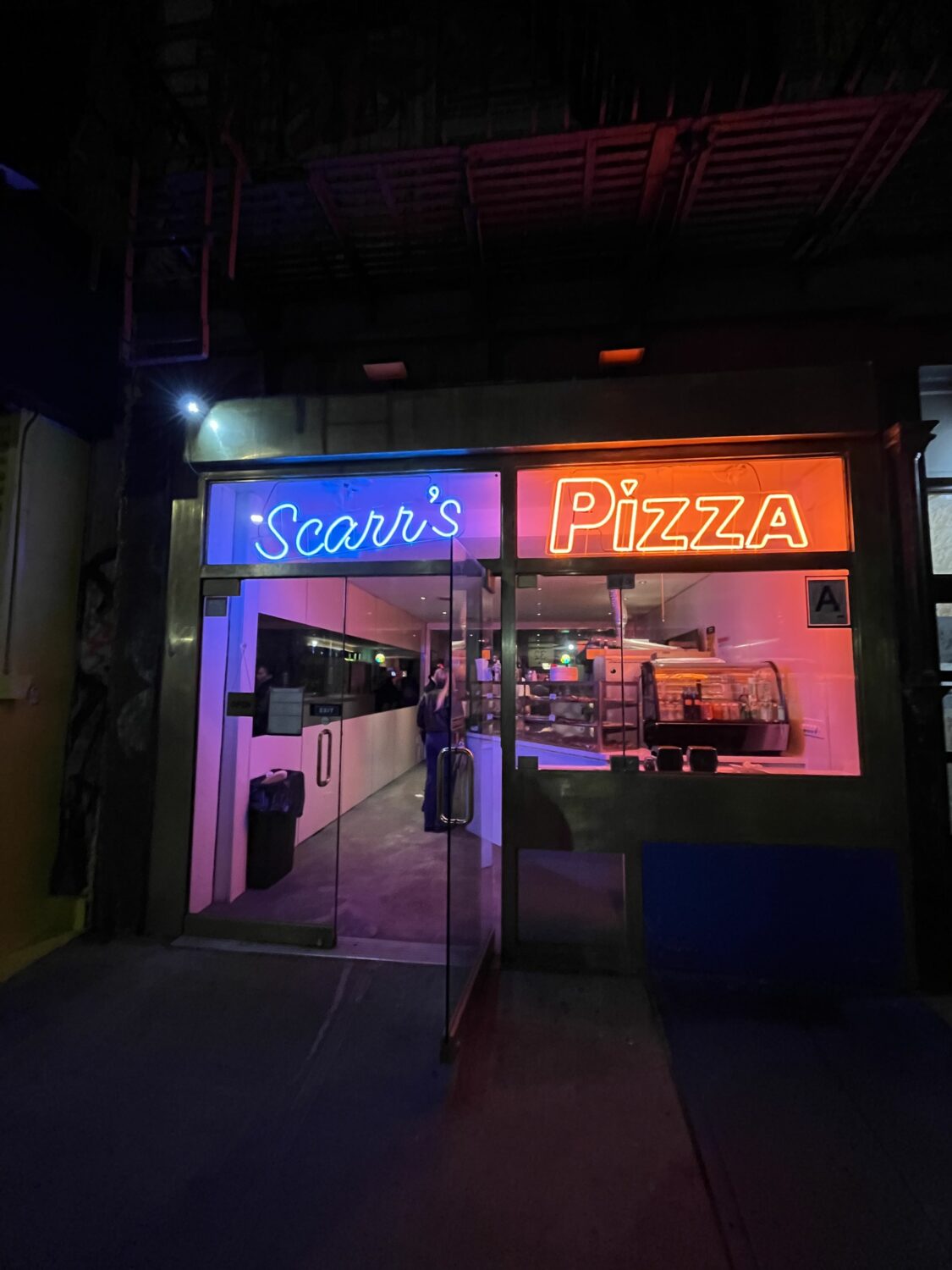 Scarr's Pizza frontage at night - blue and red neon lights. 